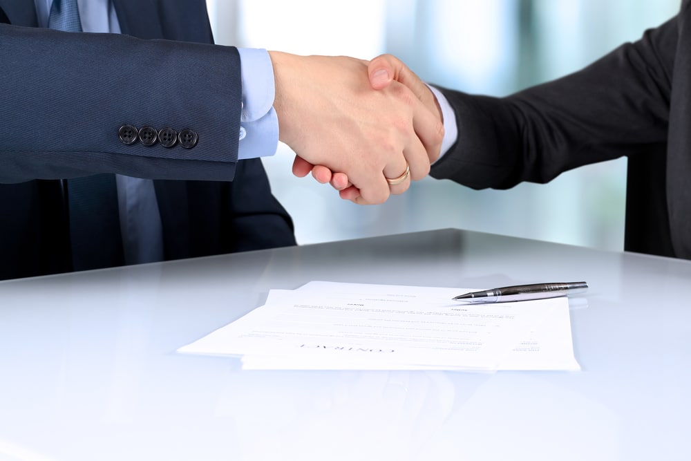 firm handshake between two colleagues after signing a contract